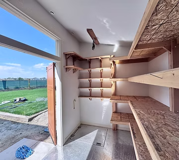 Inside the custom shed: cedar shelving, and the hatch set in the floor